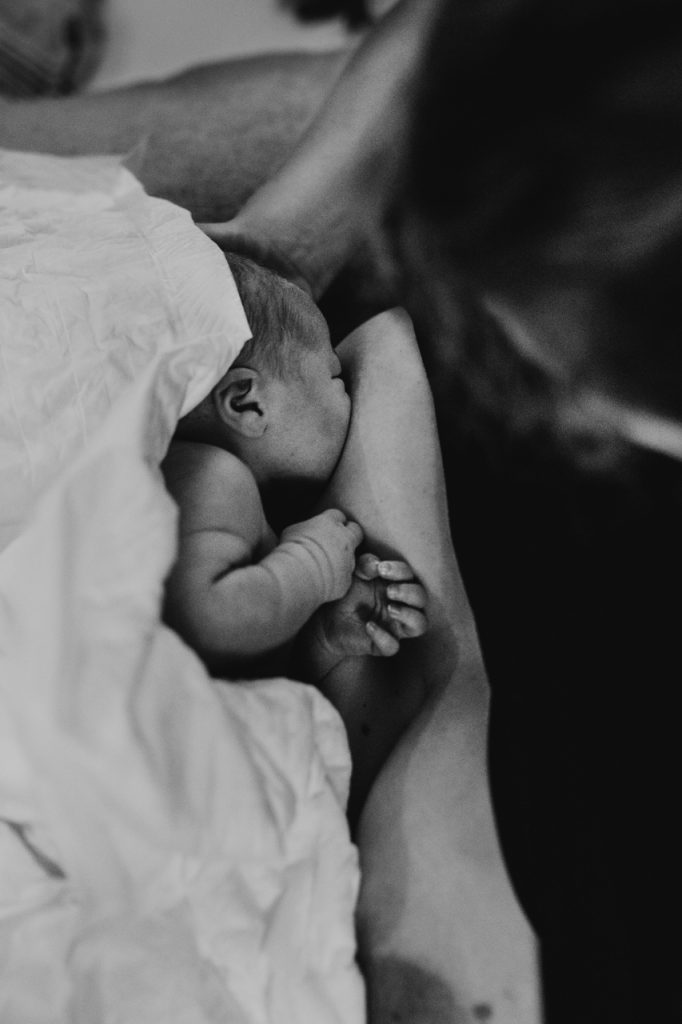 Zwart wit foto geboortefotografie pas geboren baby aan borst